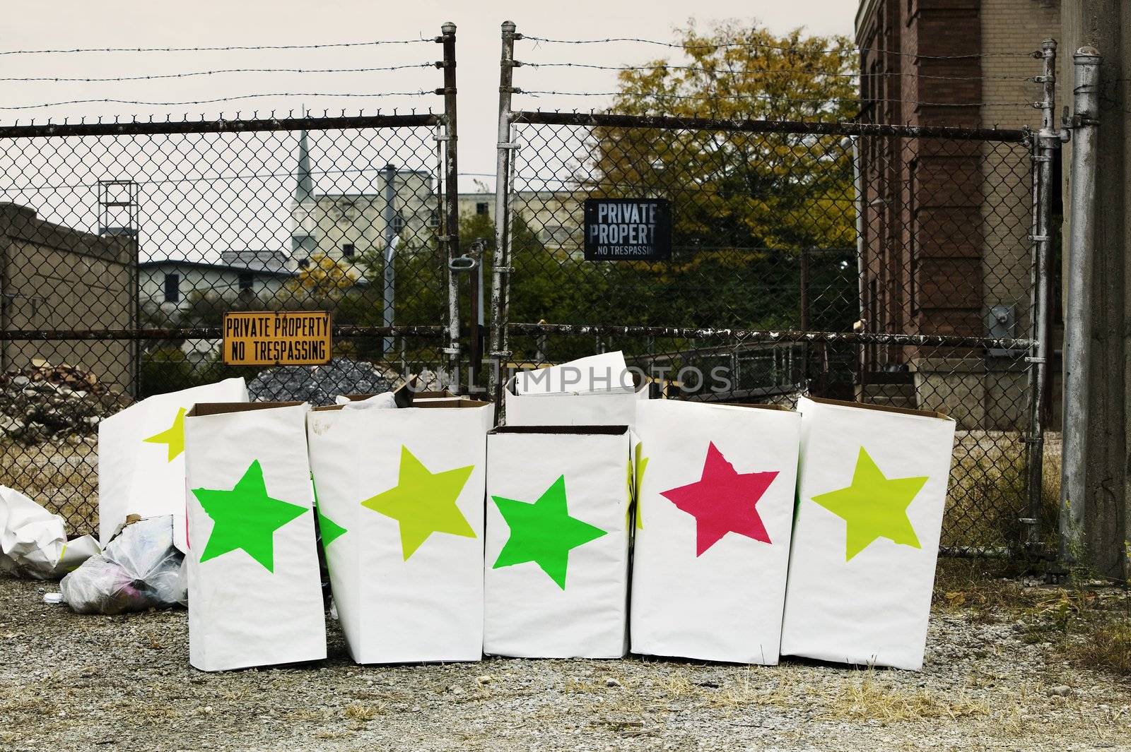 Trash boxes with brightly colored stars in front of a chain link fence.