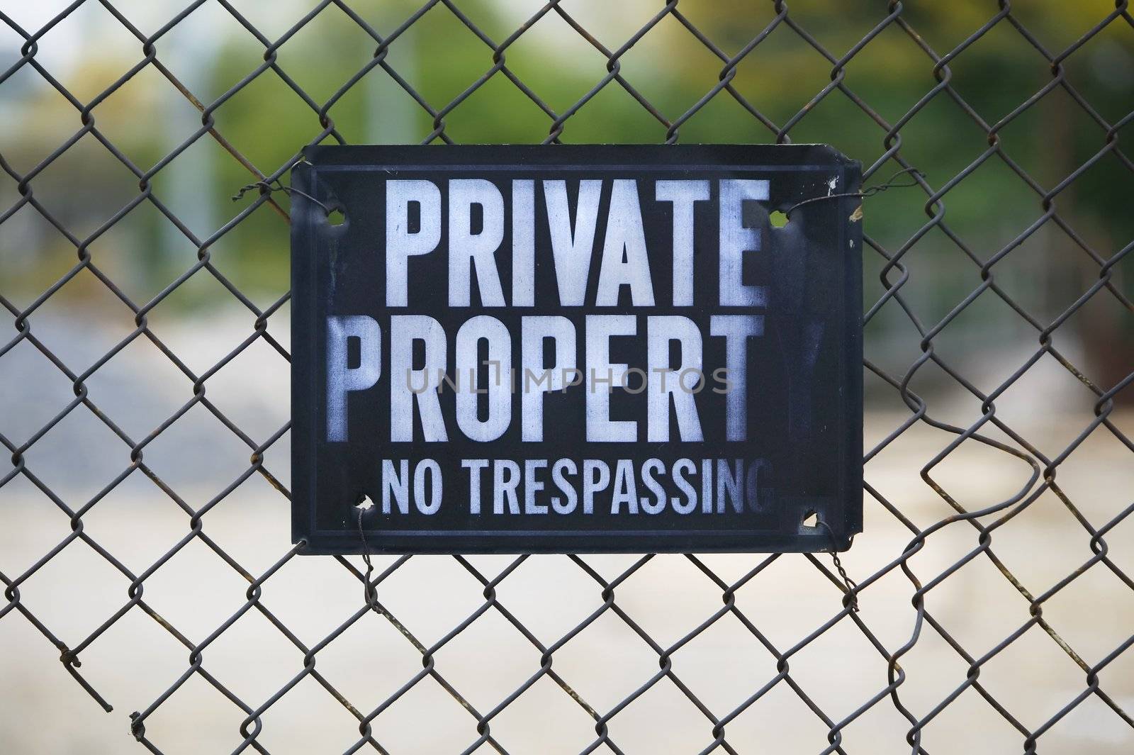 Private property sign on a rusty chain link fence.