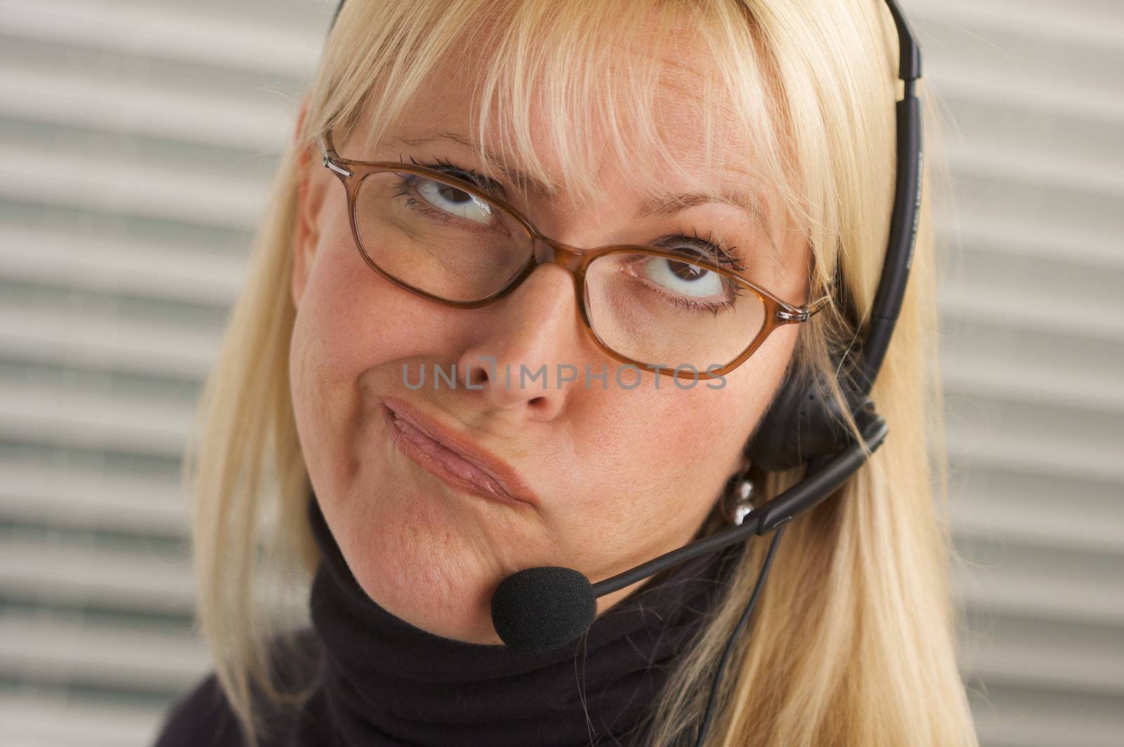 Goofy businesswoman talks on her phone headset.