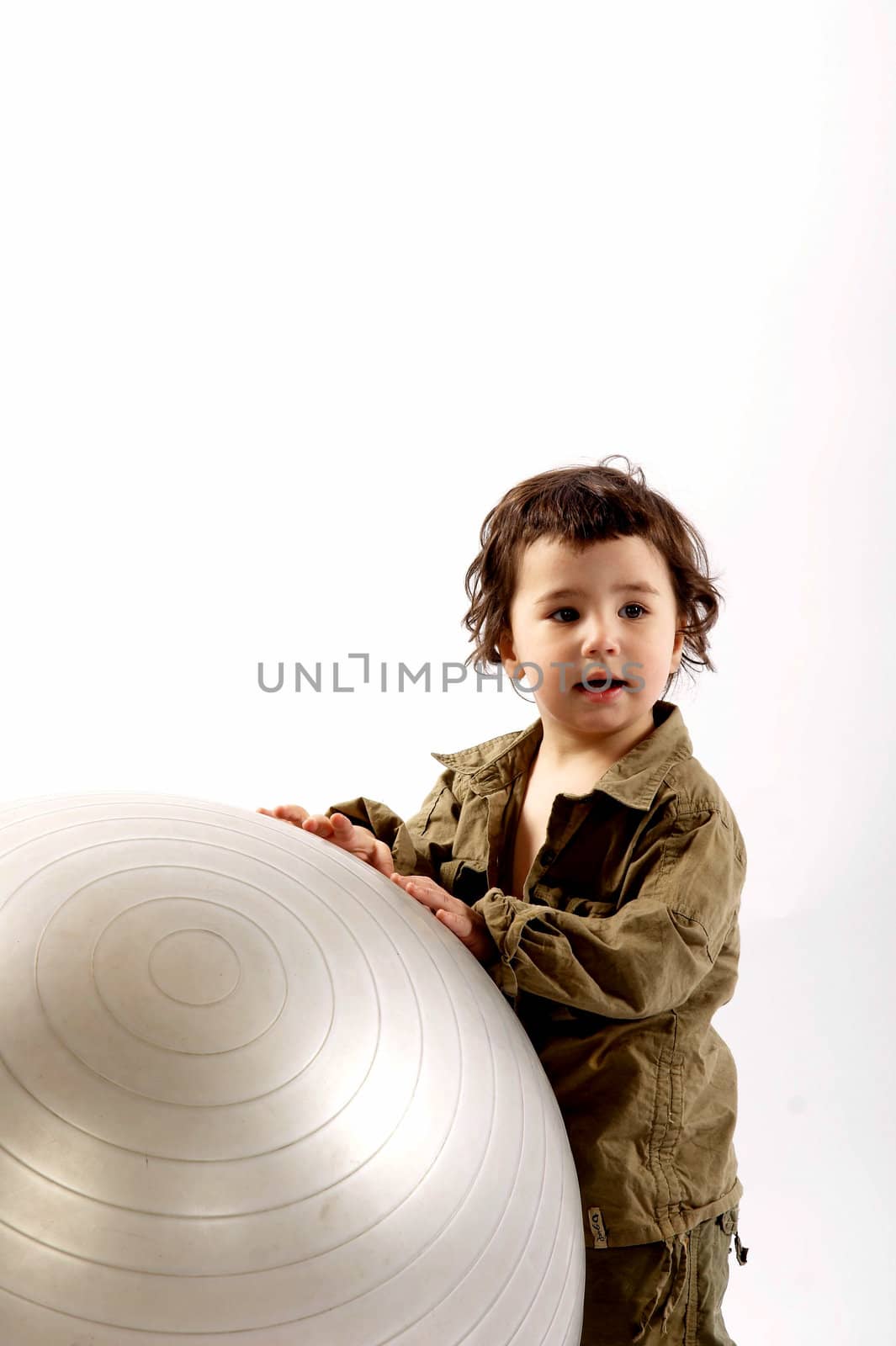 Little boy plays with a big silver ball in photo studio