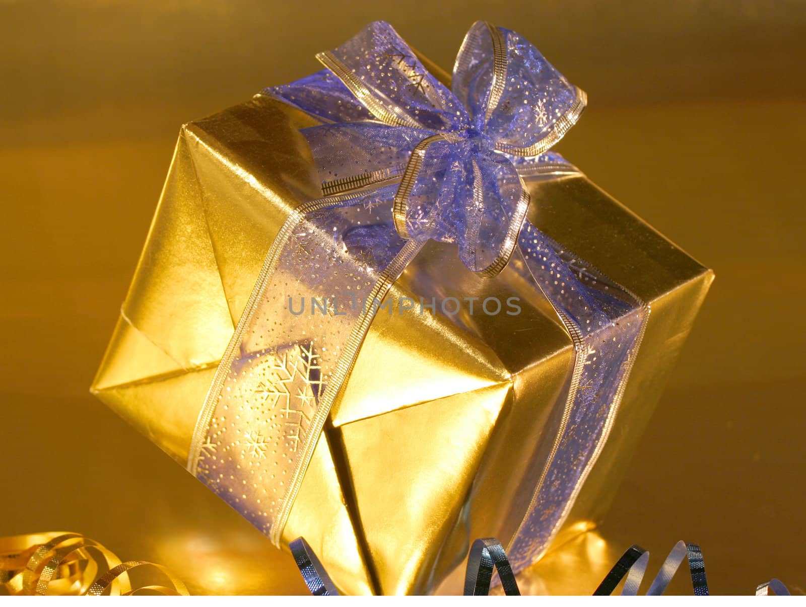 Elegant gold present with blue ribbons on gold background. by jarenwicklund