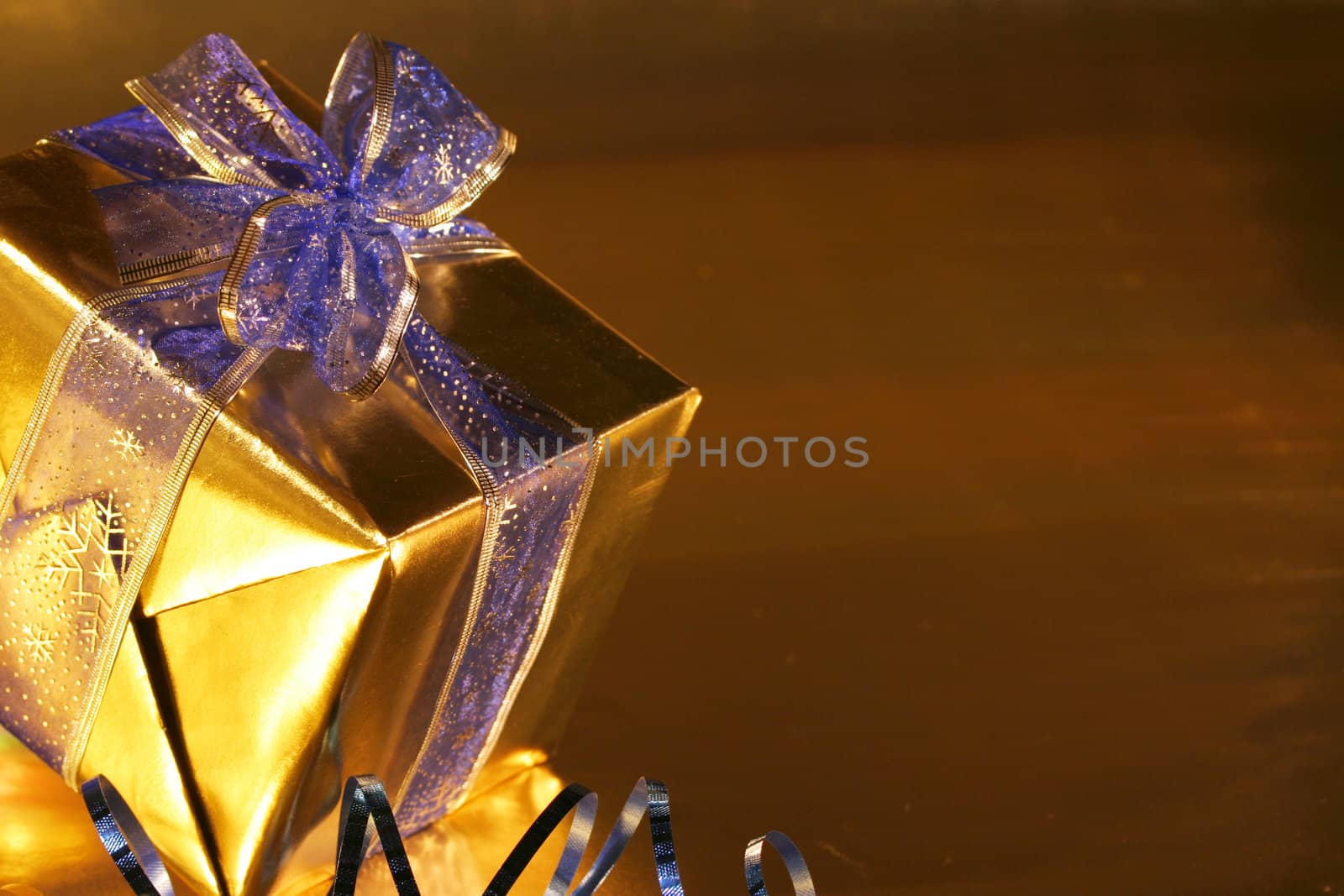 Elegant gold present with blue ribbons on  gold background.