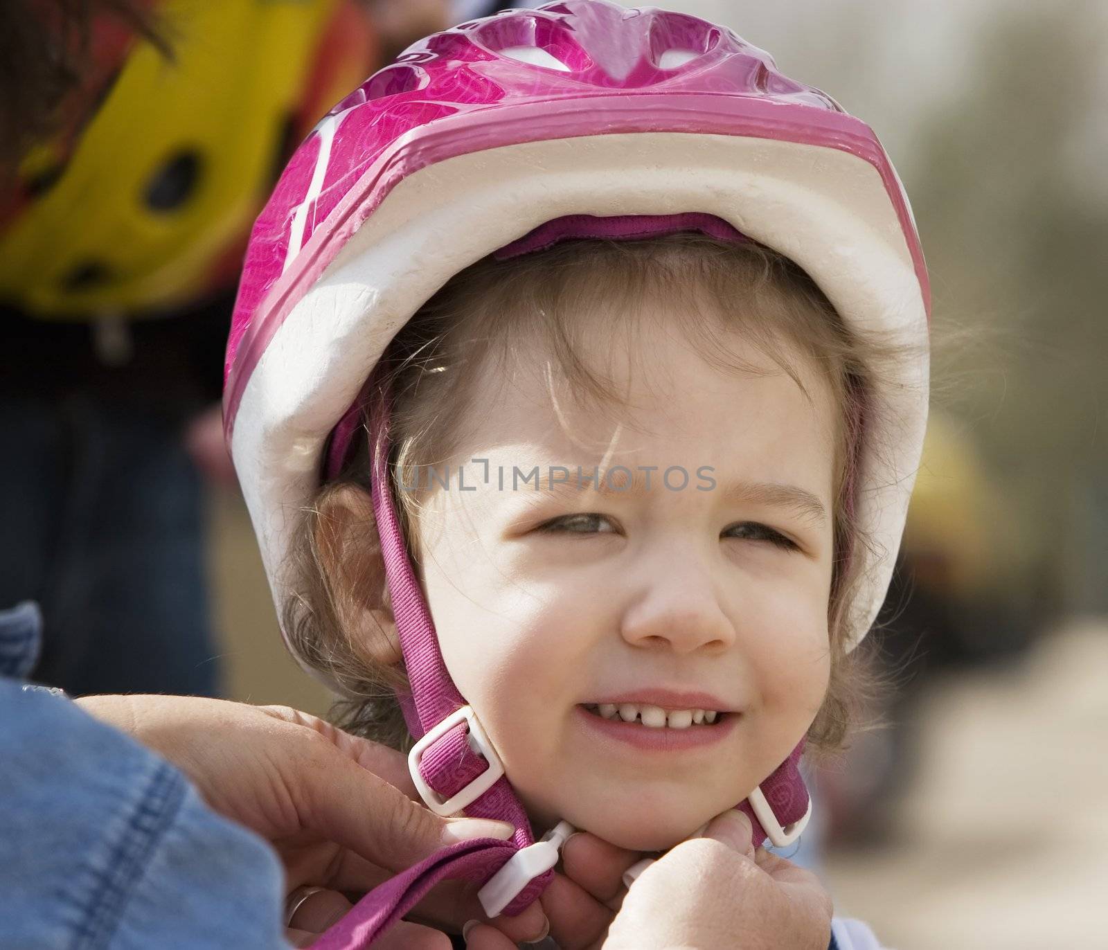 Young girl having a bicycle helmet snapped on her head smiles at the camera