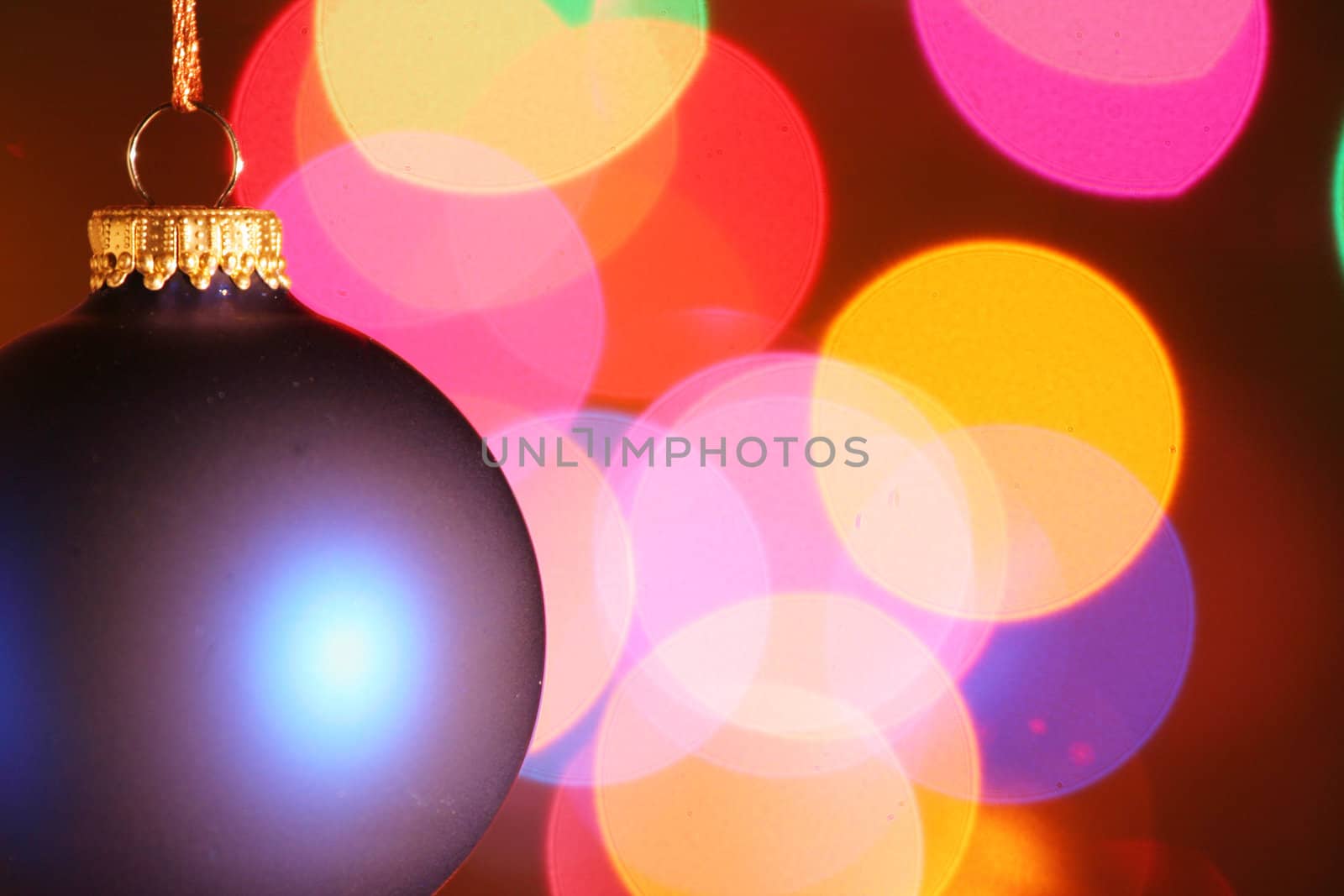 Blue frosted Christmas ornament with colorful lights in background.
