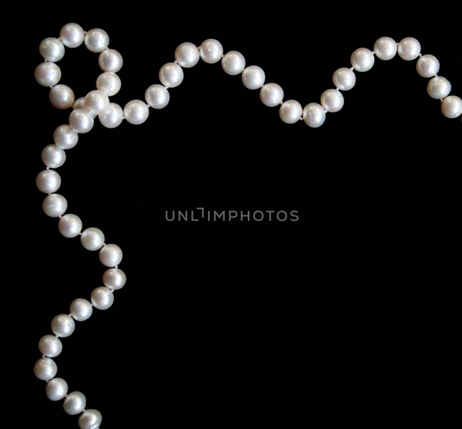 White pearls on the black silk as background 