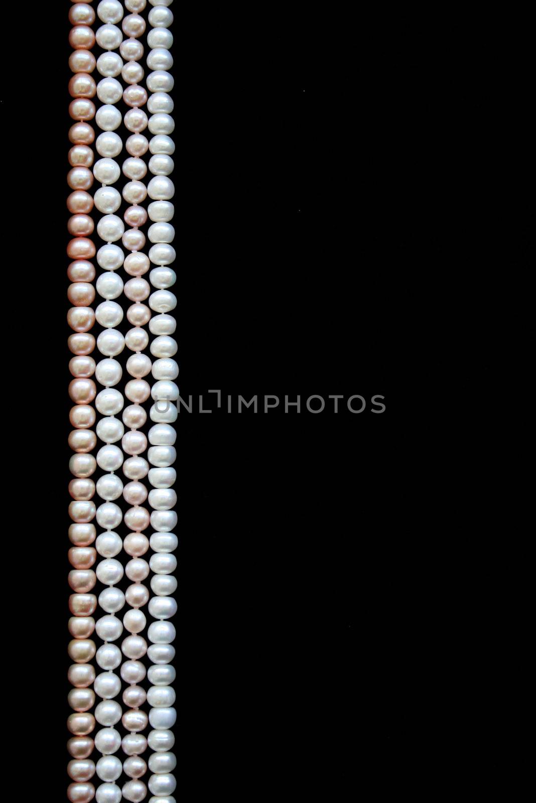 White and pink pearls on the black velvet background 
