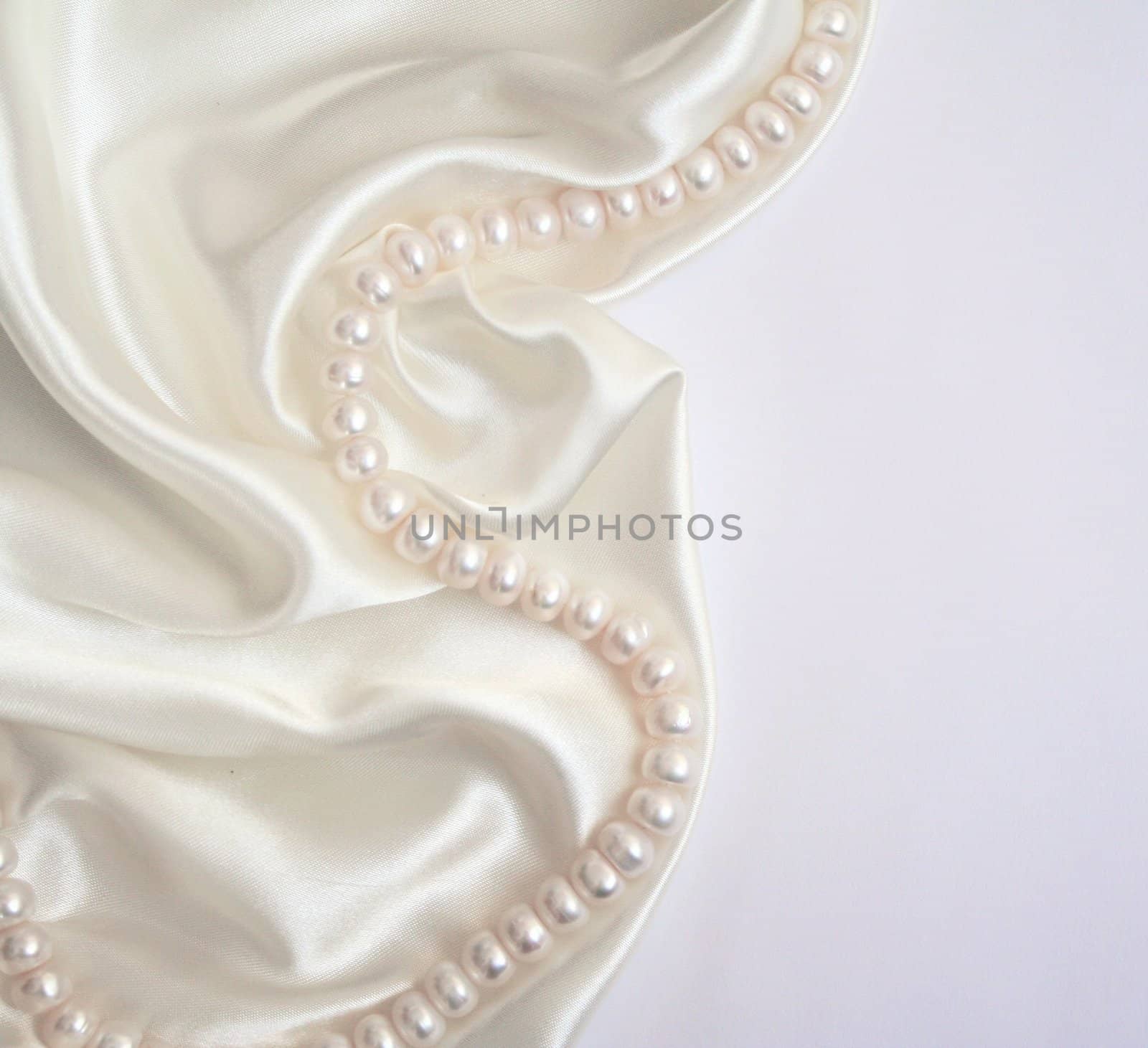 White pearls on the white silk as wedding background 