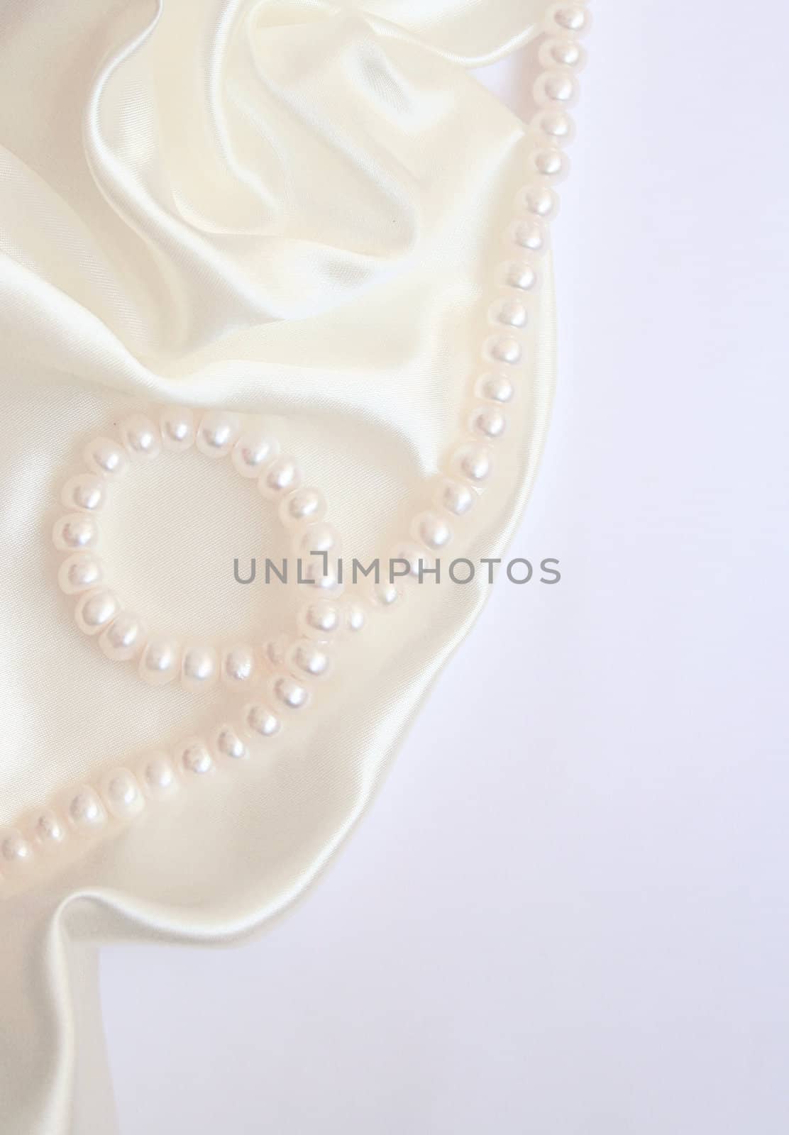 White pearls on the white silk as wedding background 