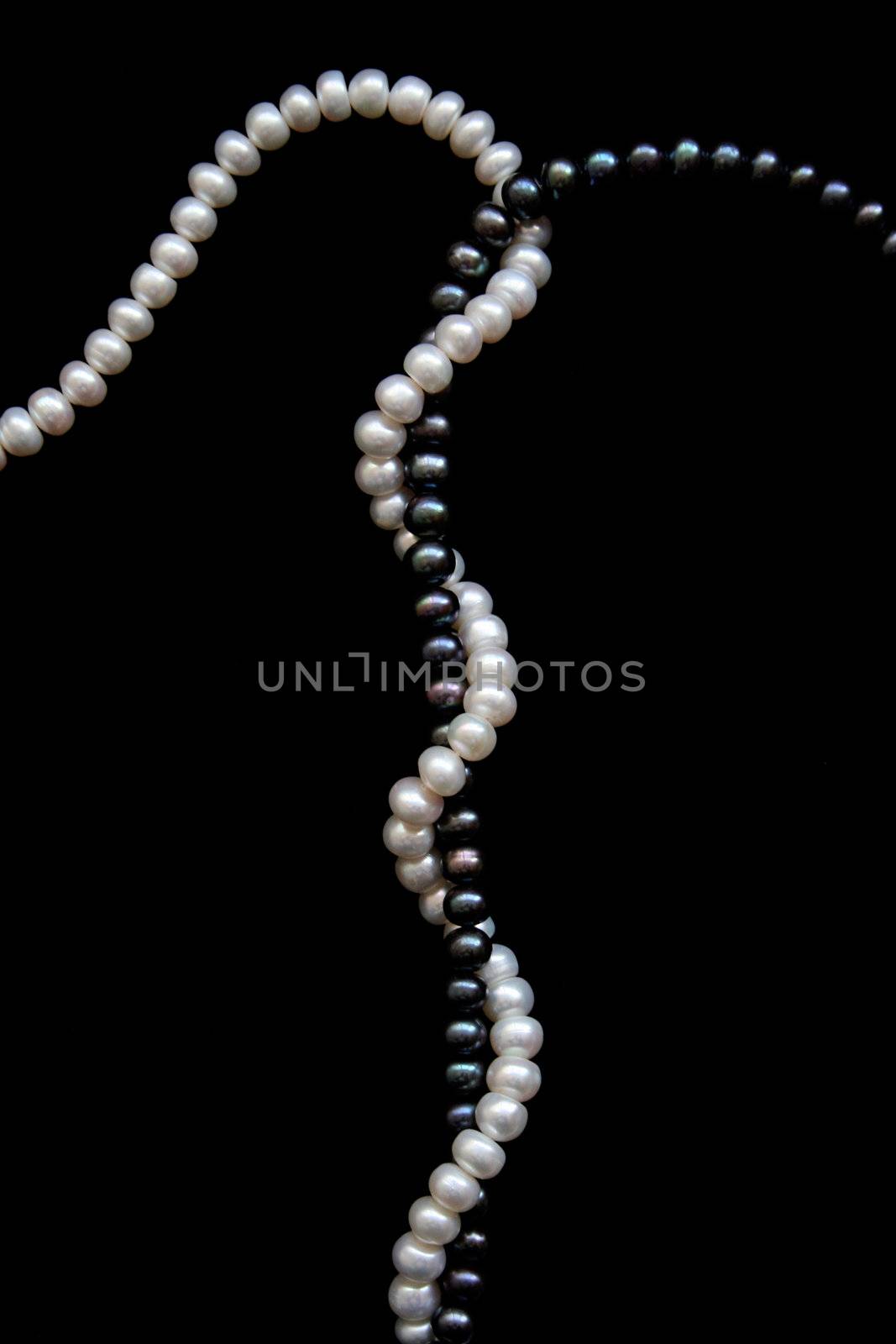 White and black pearls on a black velvet background 