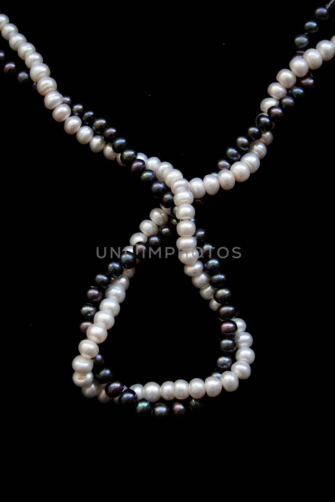 White and black pearls on a black velvet background 