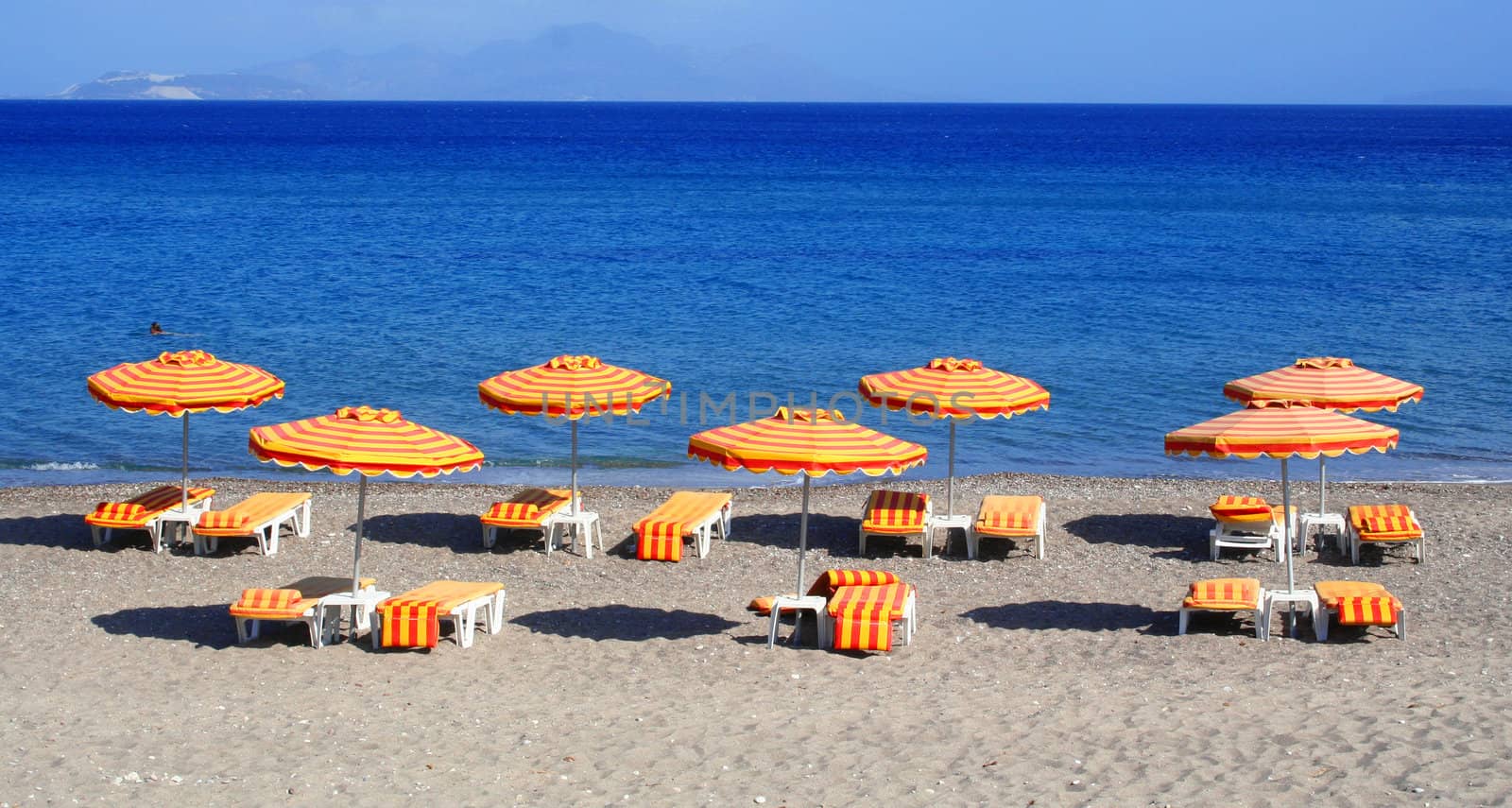 Greece. Kos island. Kefalos beach. Orange chairs and umbrellas on the beach 