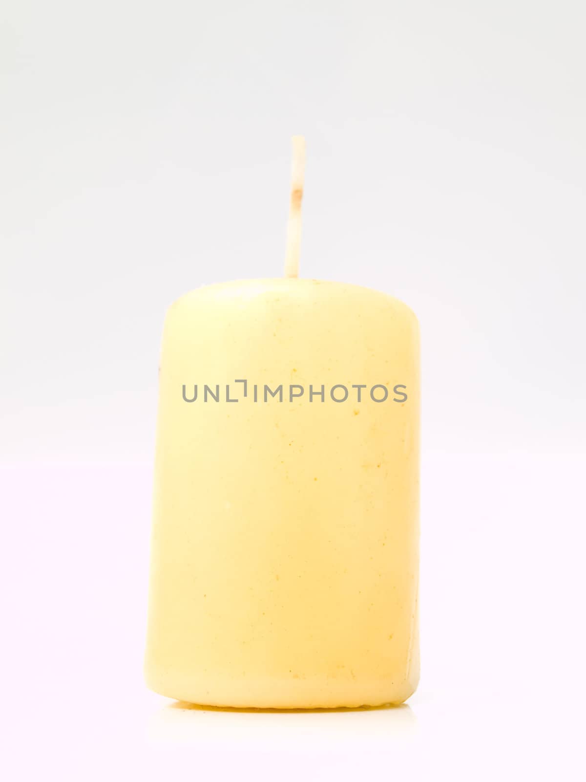 Tall yellow wax candle on white