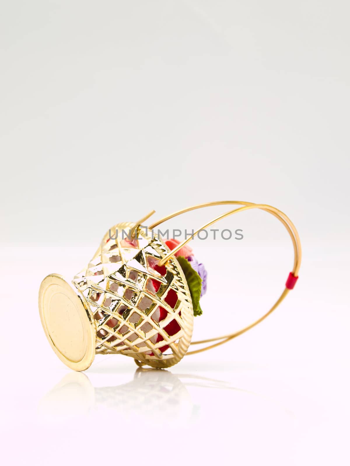 A miniature metalic wicker decorated by roses on a red velvet isolated on white background