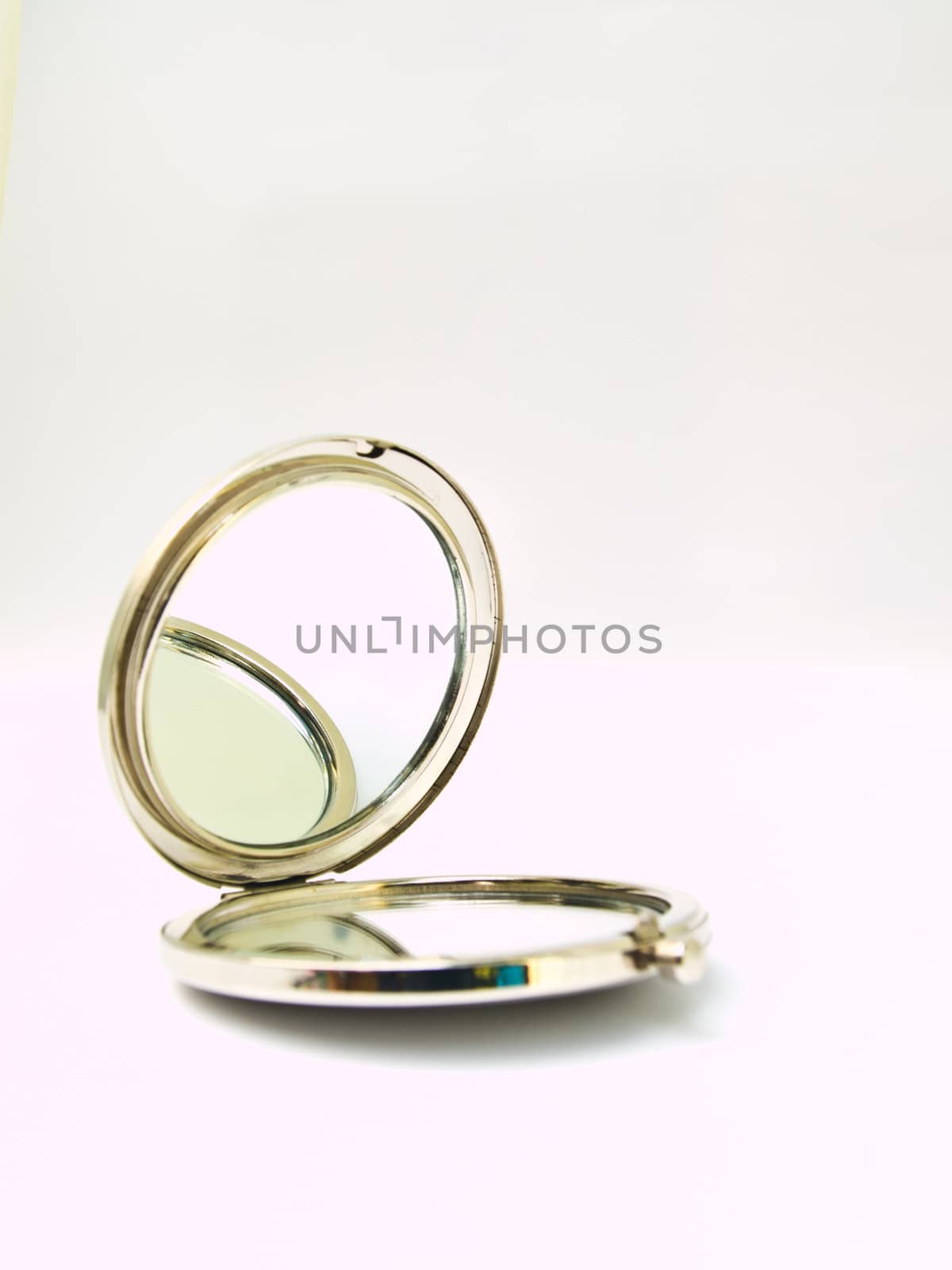 A metalic pocket makeup mirror isolated on white background