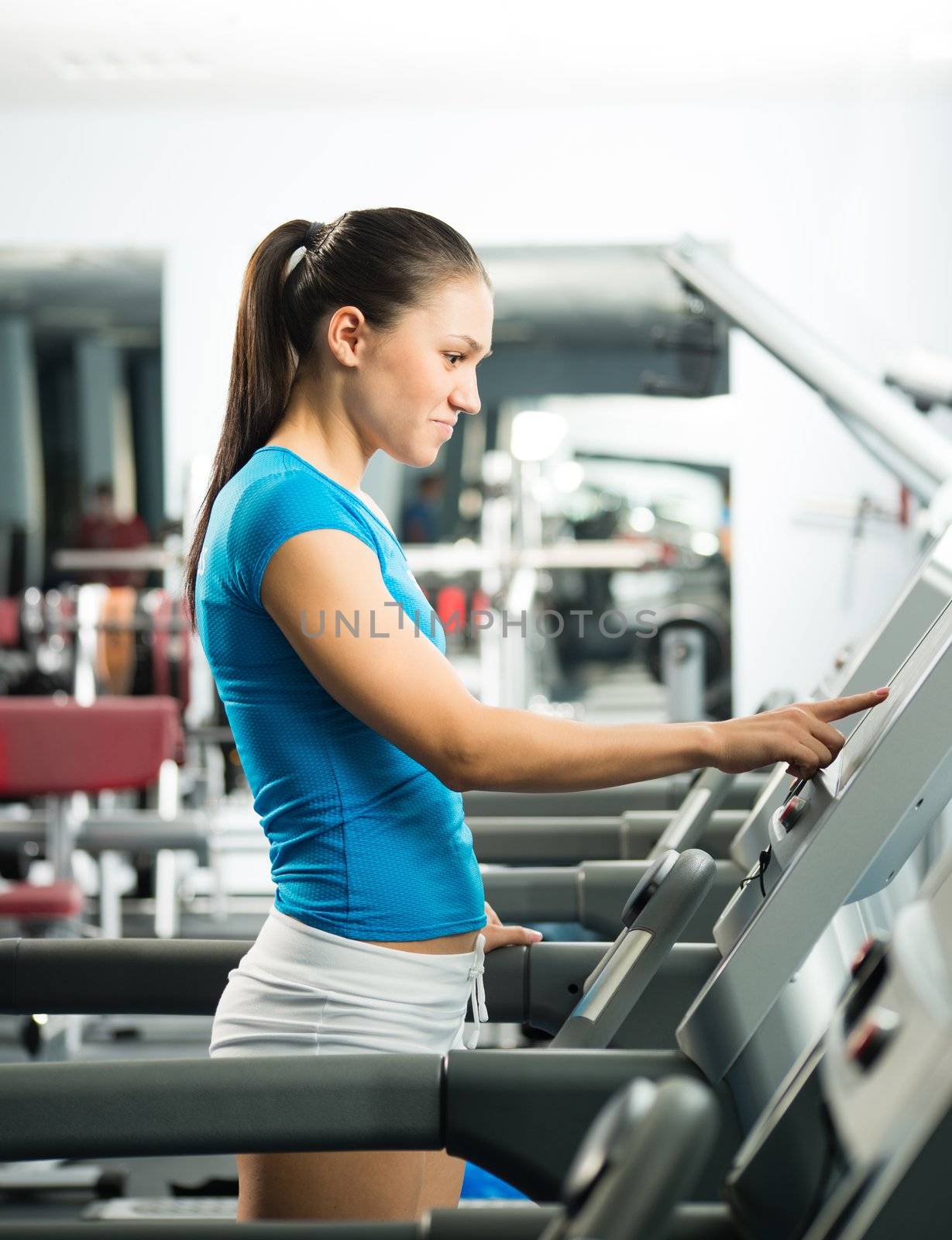 attractive young woman adjusts the treadmill by adam121