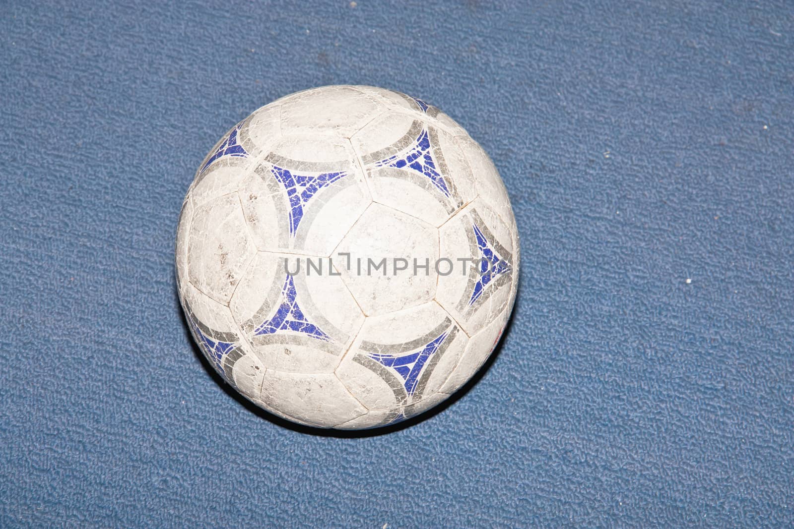 Old soccer ball on background blue grass.