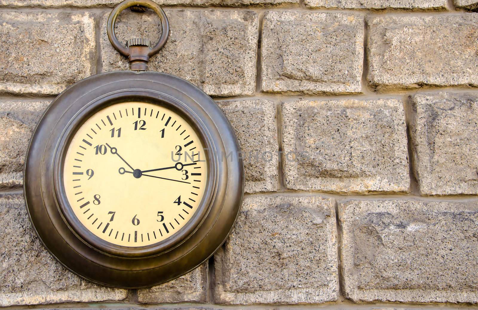 Retro metal clock on a stone wall