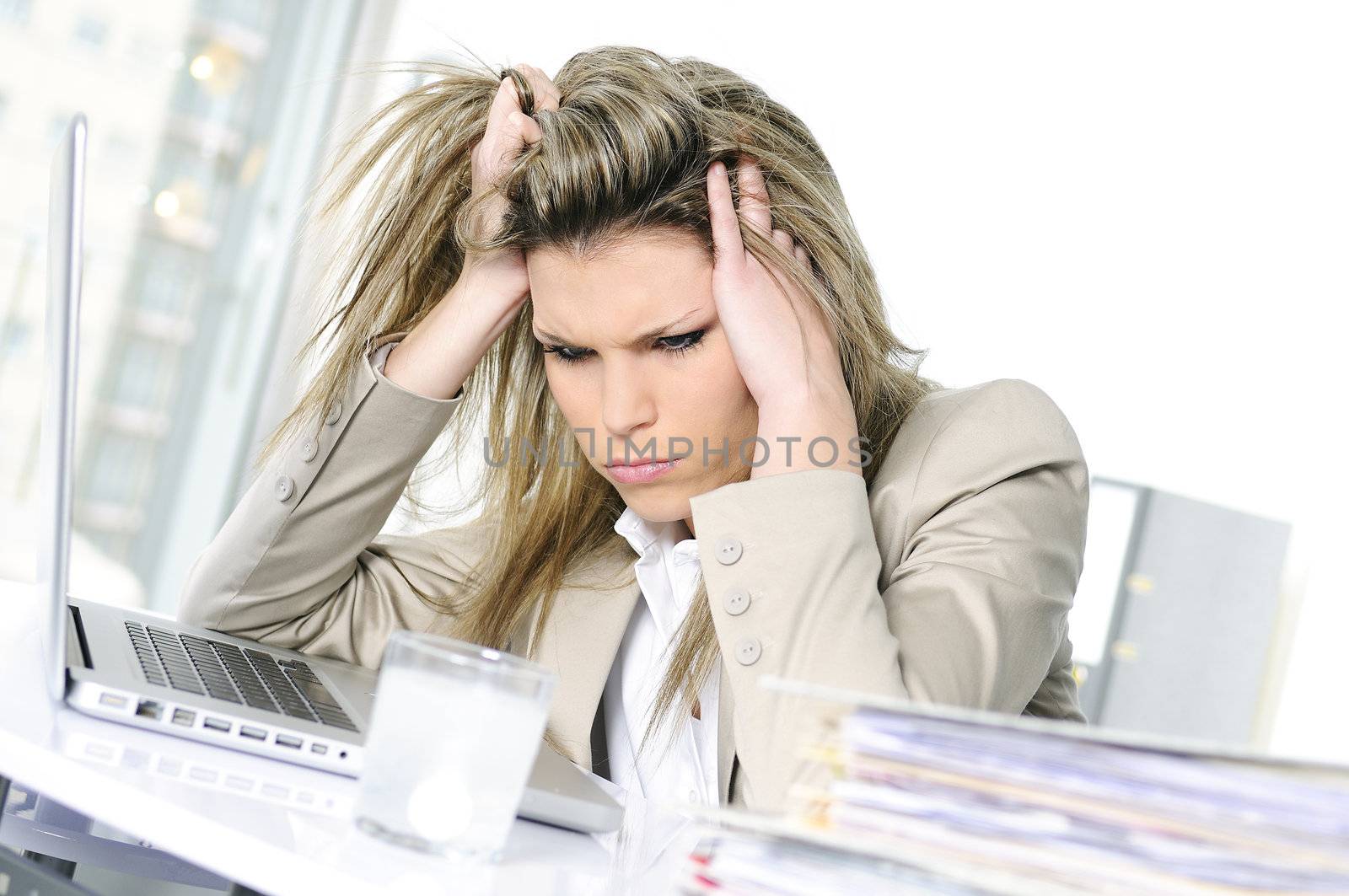 young woman stressed at work, taking an aspirin cahet