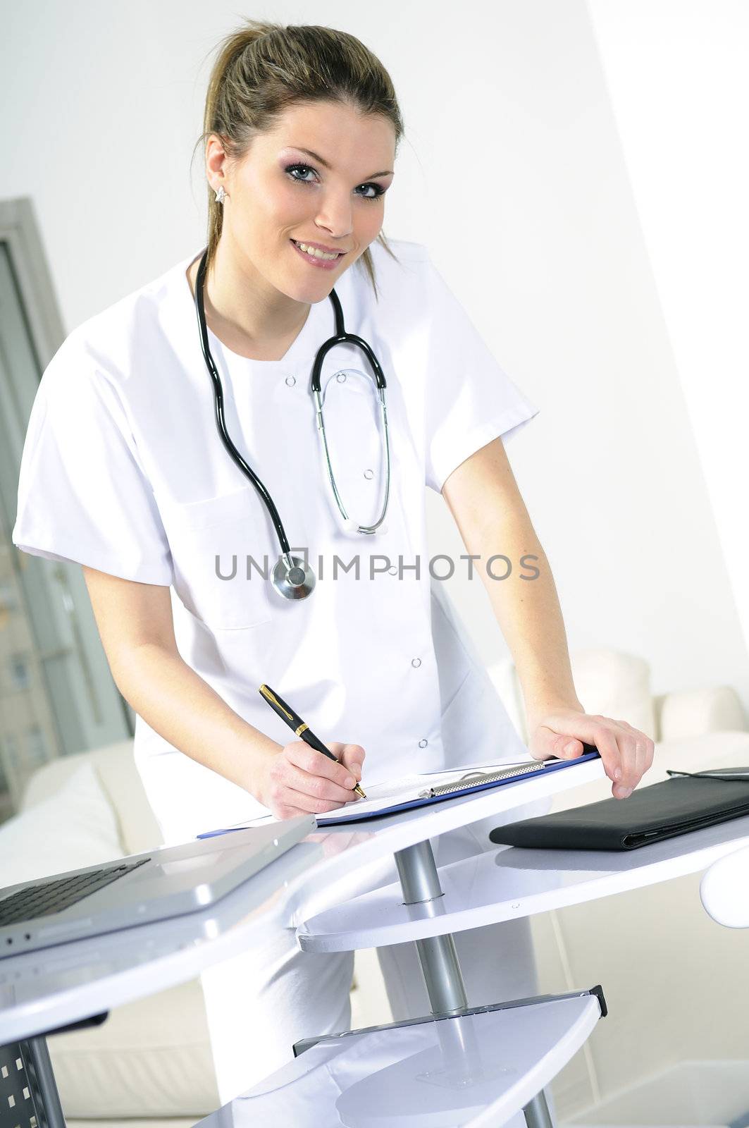 Woman Doctor Seated At Desk wearing a stethoscope by ventdusud