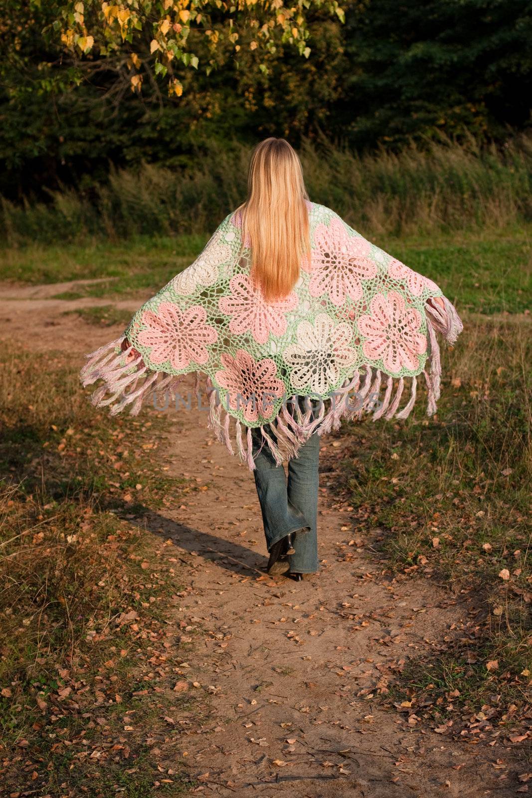 A walking girl in a swal and jeans in a forest
