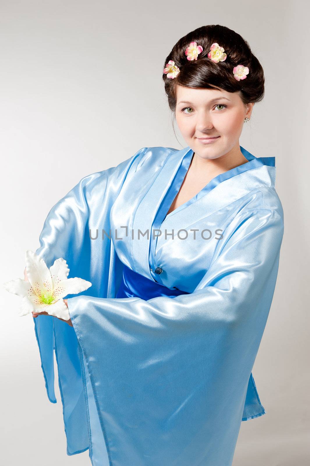Woman in blue kimono with lily in hands.