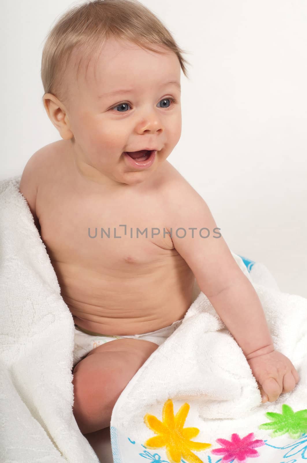 Lttle boy in white blanket with flowers in studio