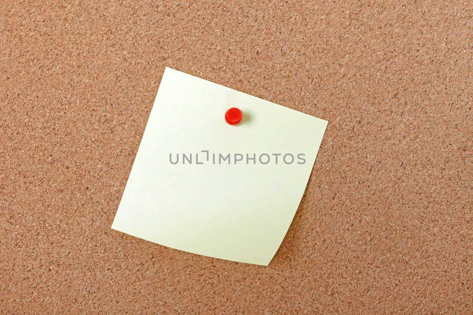 Yellow note paper attached with red pin to corkboard. Empty spac by borodaev