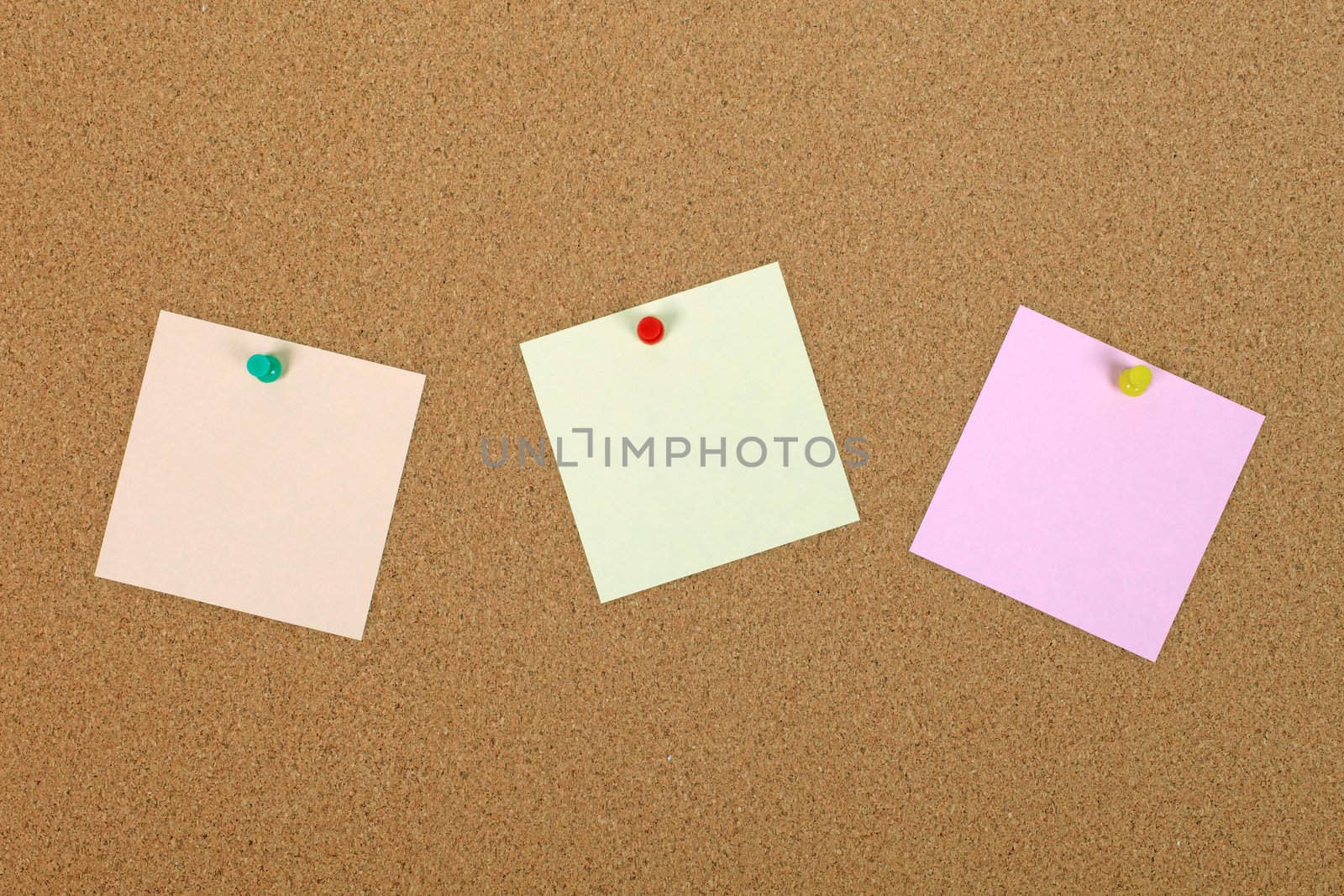 Three note papers attached to cork board with pins.