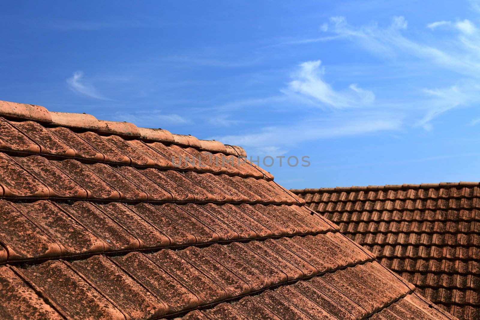 Old tiled roof and beautiful blue sky. Abstract photo as background or backdrop.