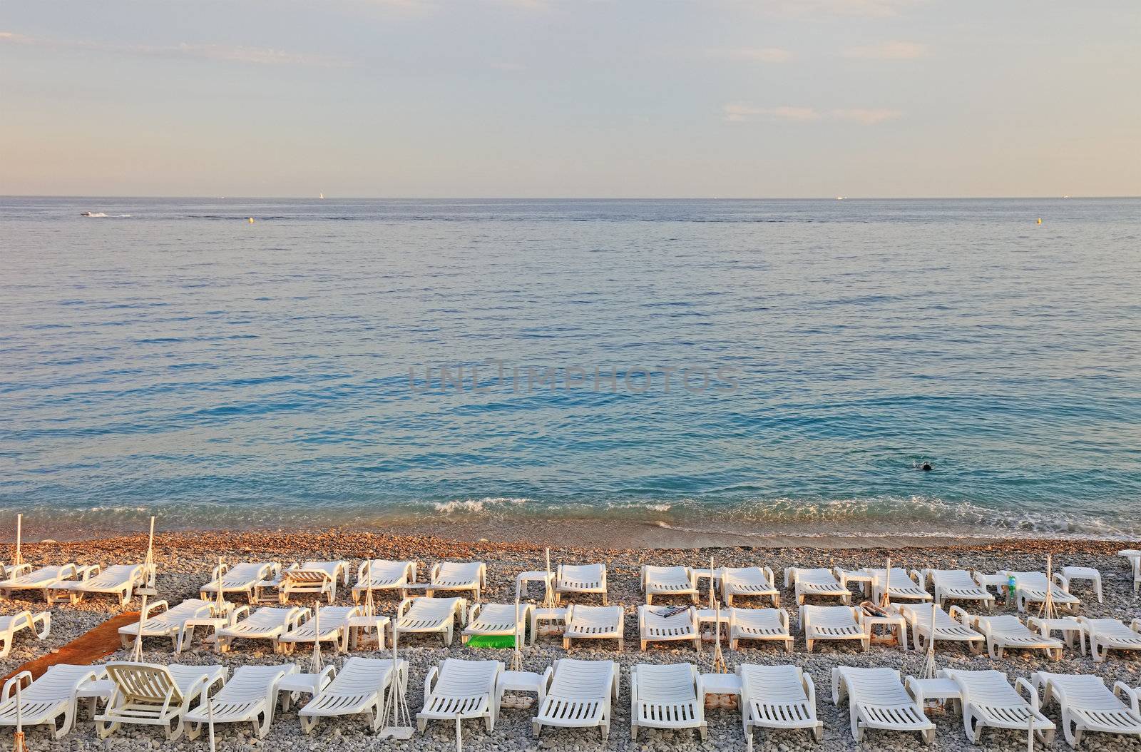 Lot of sun  loungers on the beach of Nice, France. by borodaev