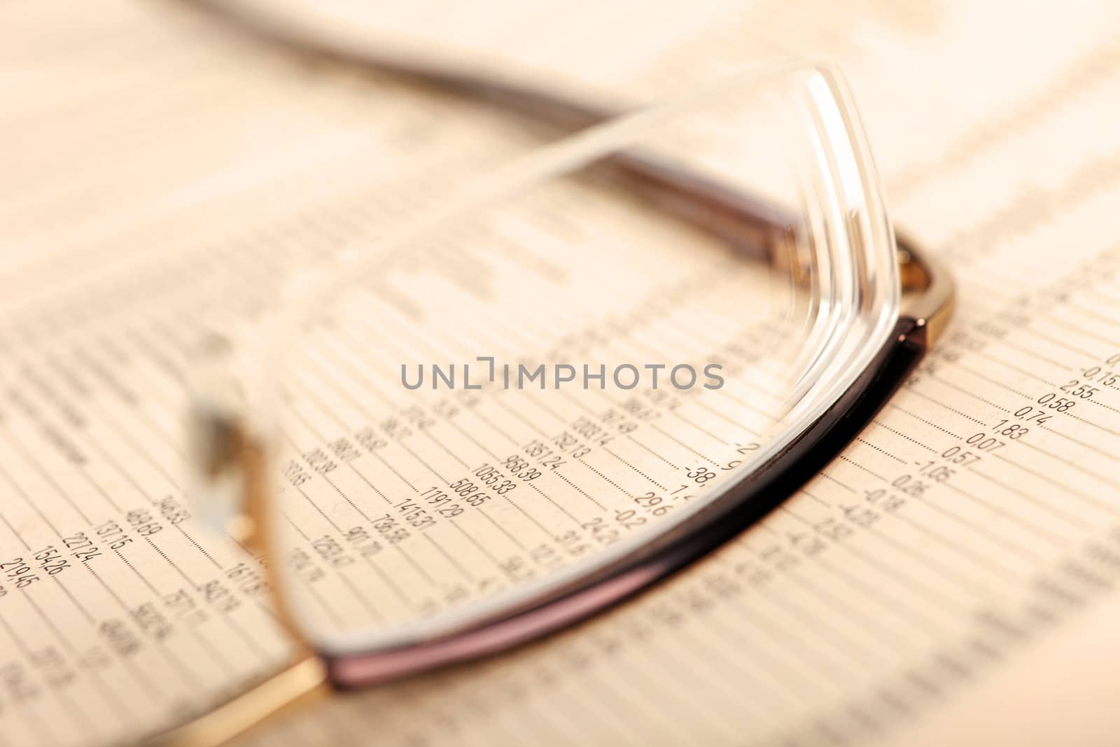 Macro of financial data through eyeglasses, laying on newspaper. by borodaev