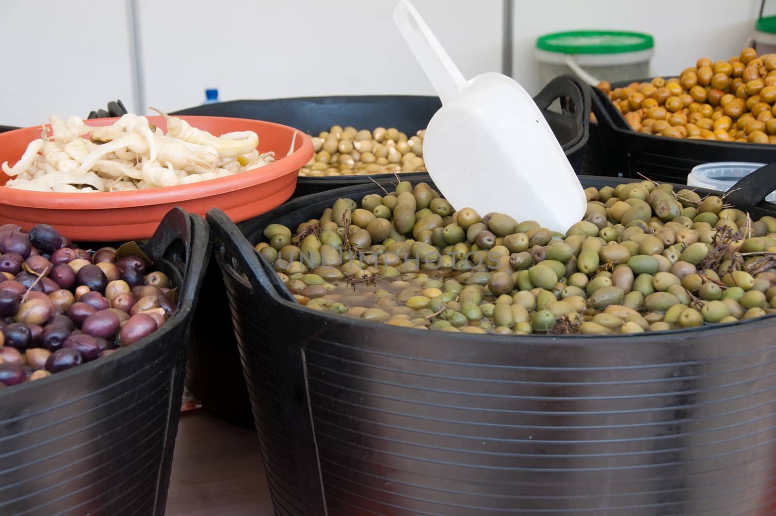 Different sorts of olives in big black barrels