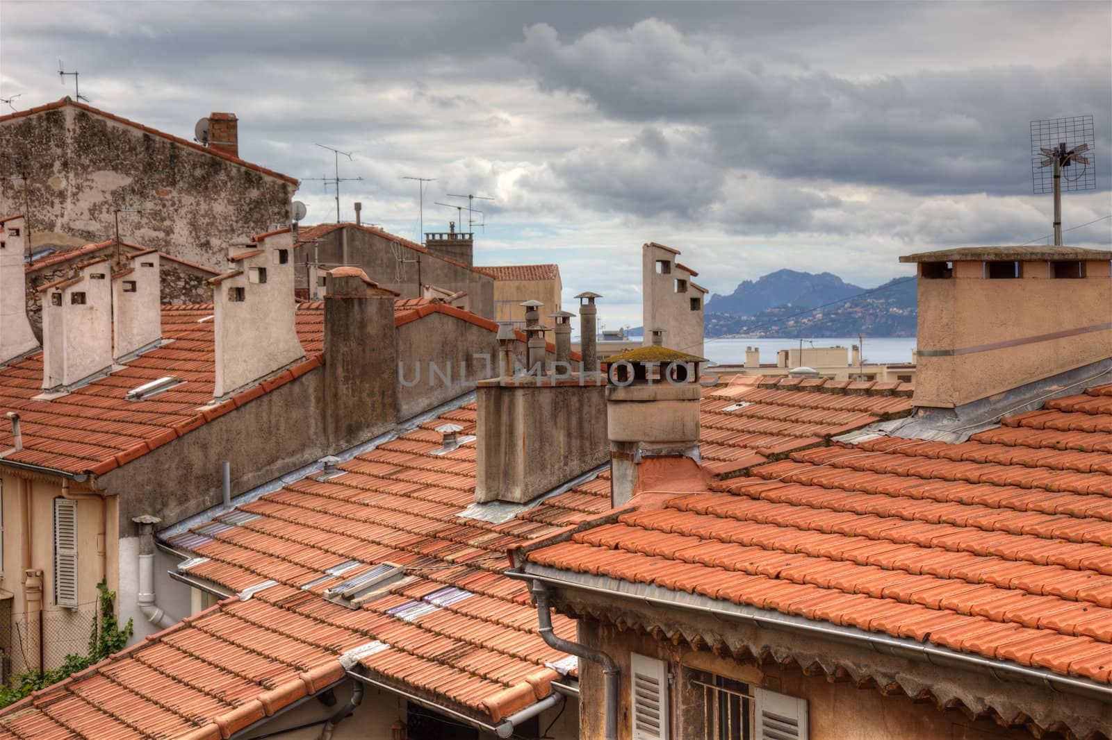 Old houses with tiled roof and dramatic cloudy sky. Cannes, France before festival during springtime.