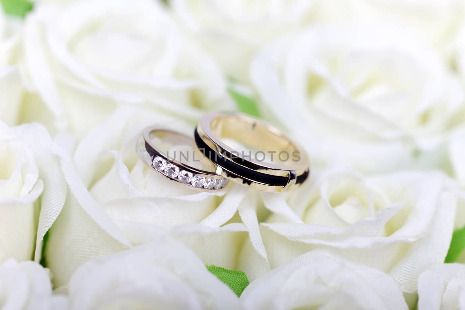 Two wedding rings on white roses bouquet. by borodaev