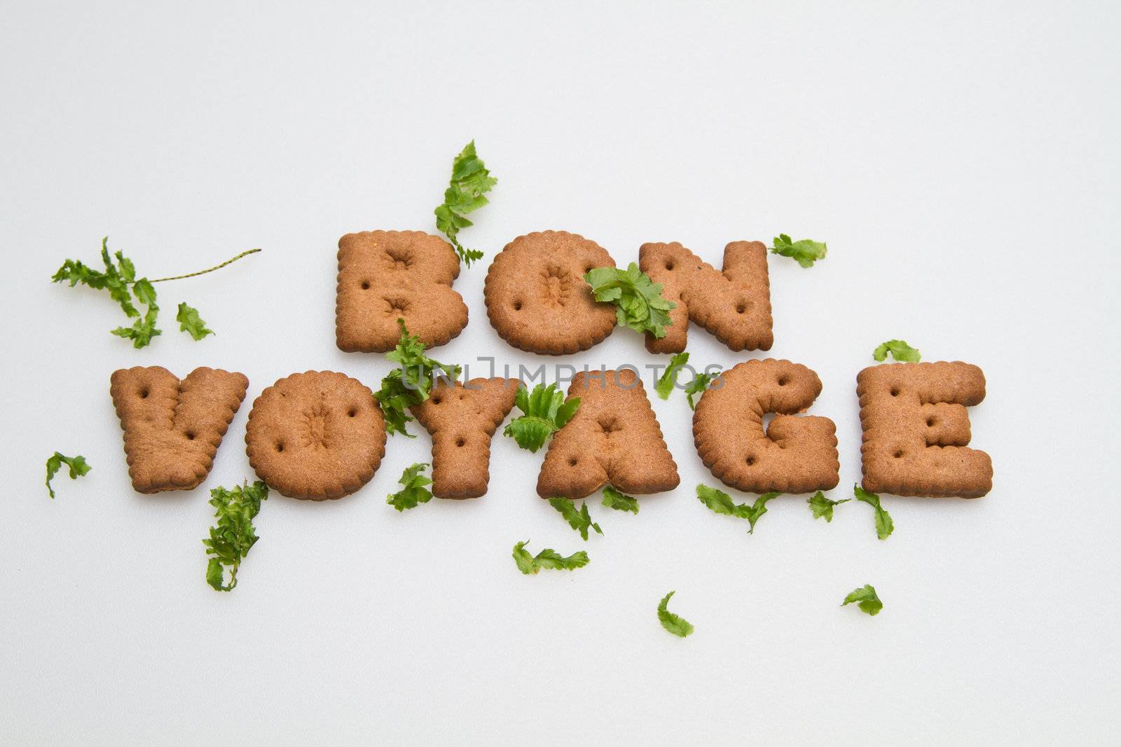 Bon Voyage phrase by brown biscuits and leaves on white surface