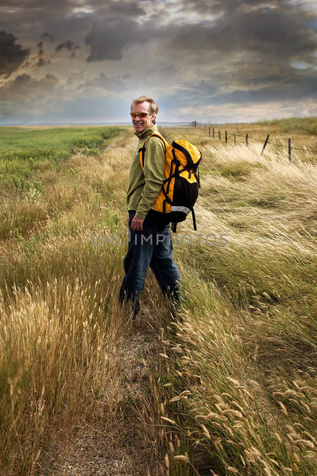 Man looking back and smiling on a prairie country road 