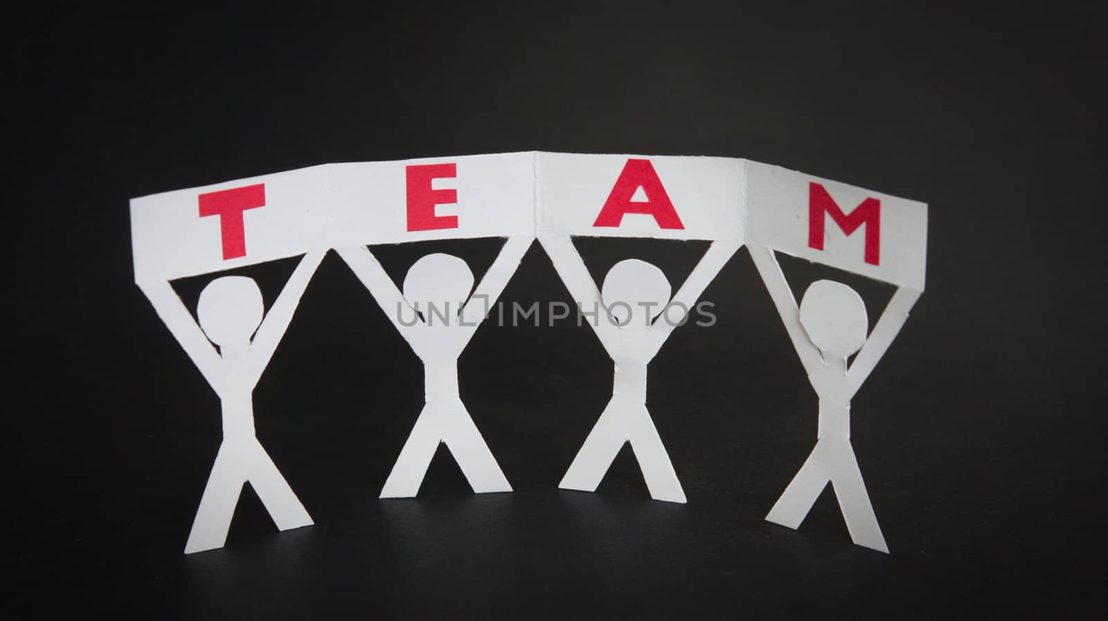 Paper silhouettes holding a Team sign by kbuntu