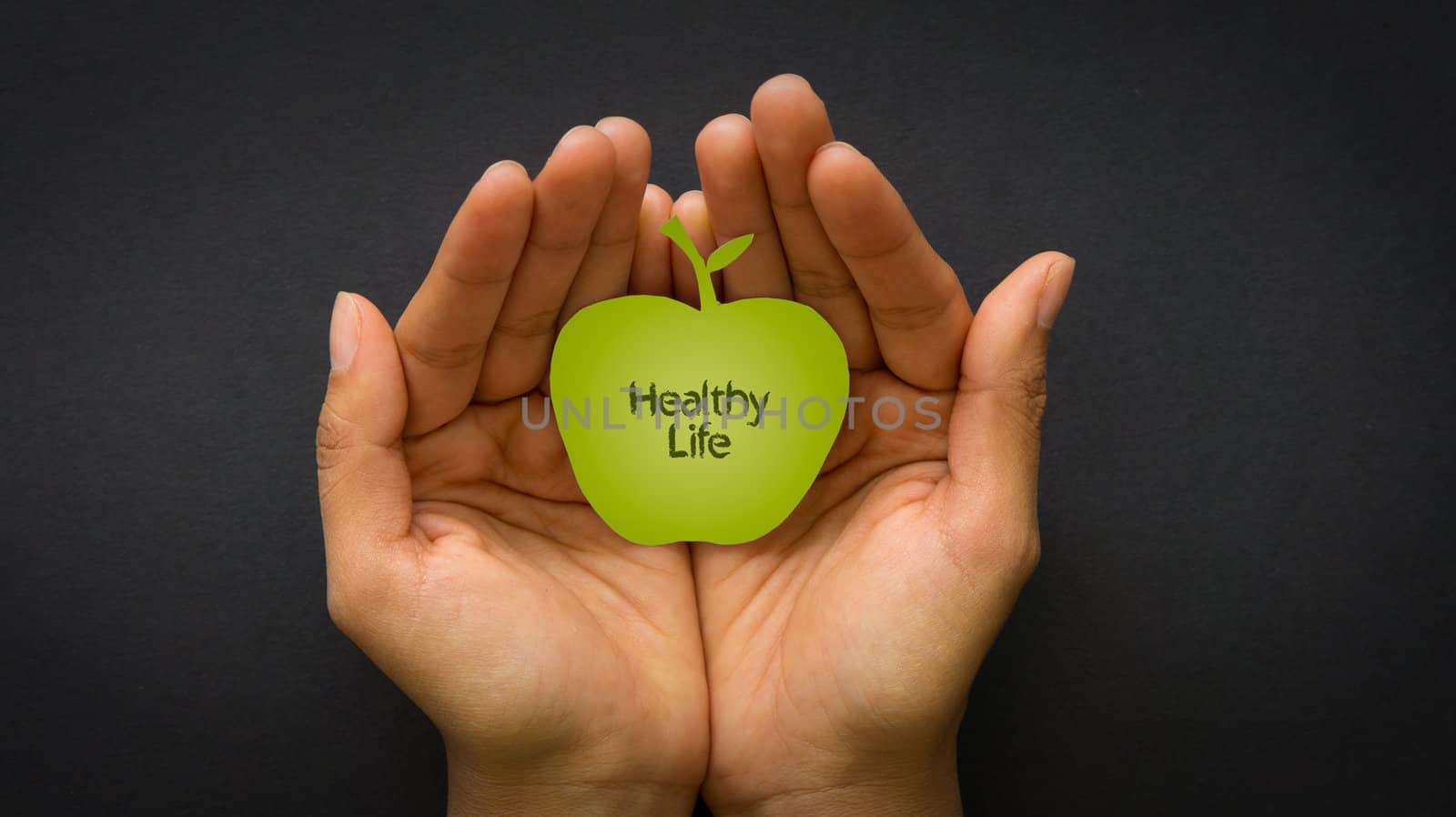 Hand holding a healthy Life Apple on black background