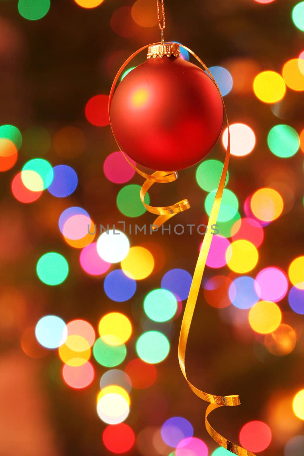 Red frosted Christmas ornament with colorful lights in background.