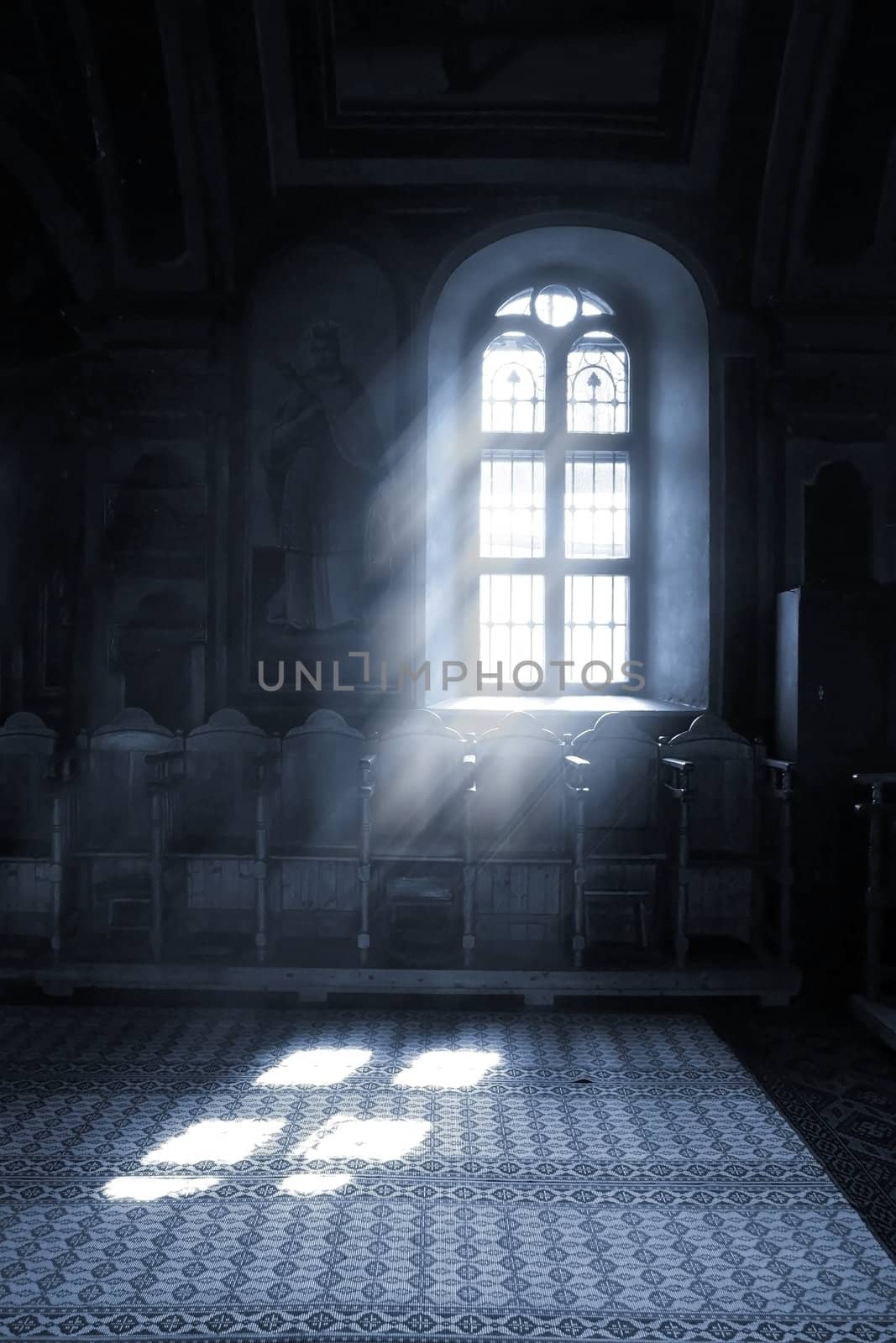 Shafts of light stream through stained glass window inside a church