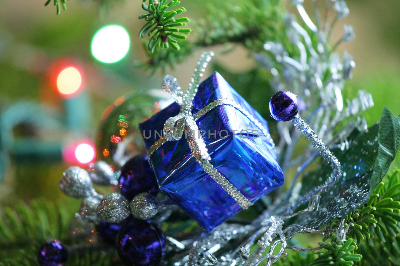 Blue present ornament nestled in CHristmas tree.