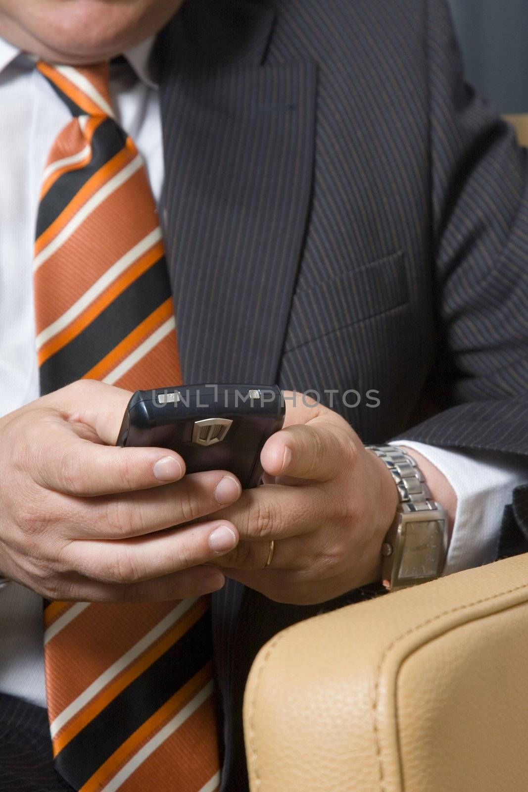 Businessman sitting in chair typing on his mobile phone
