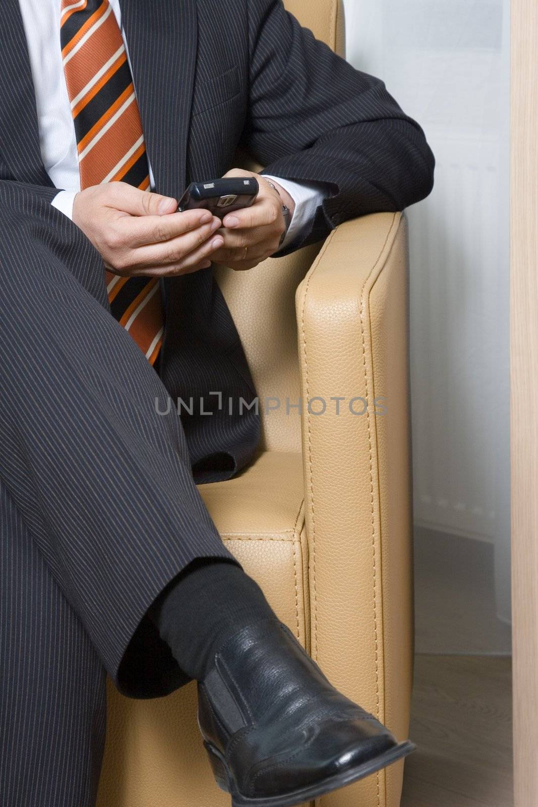 Businessman sitting in chair texting on his mobile phone