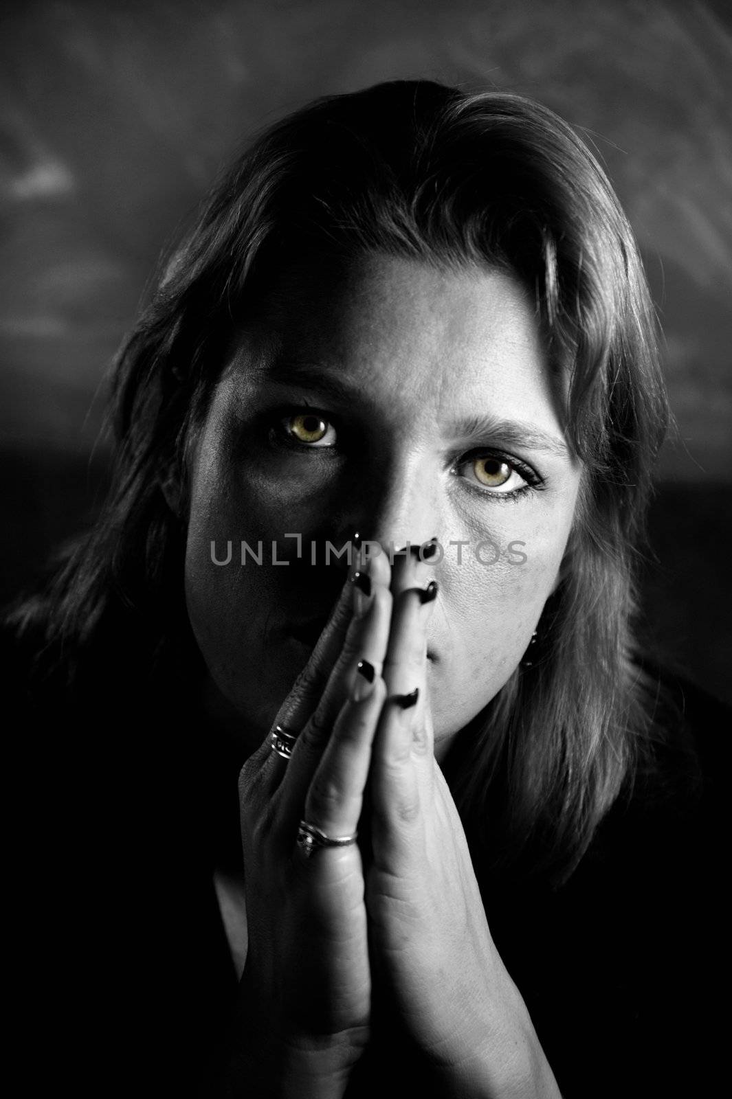 Portrait of a blonde woman with her hands folded in front of her face.