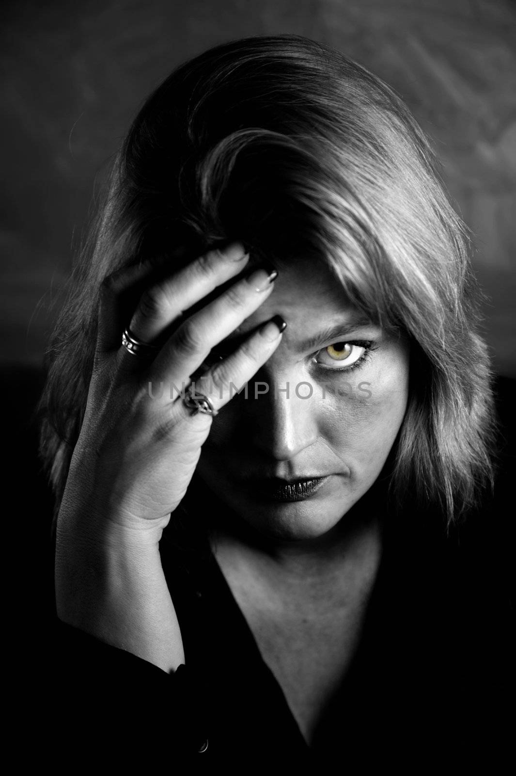 Close up of blonde woman in a studio setting touching her temple.