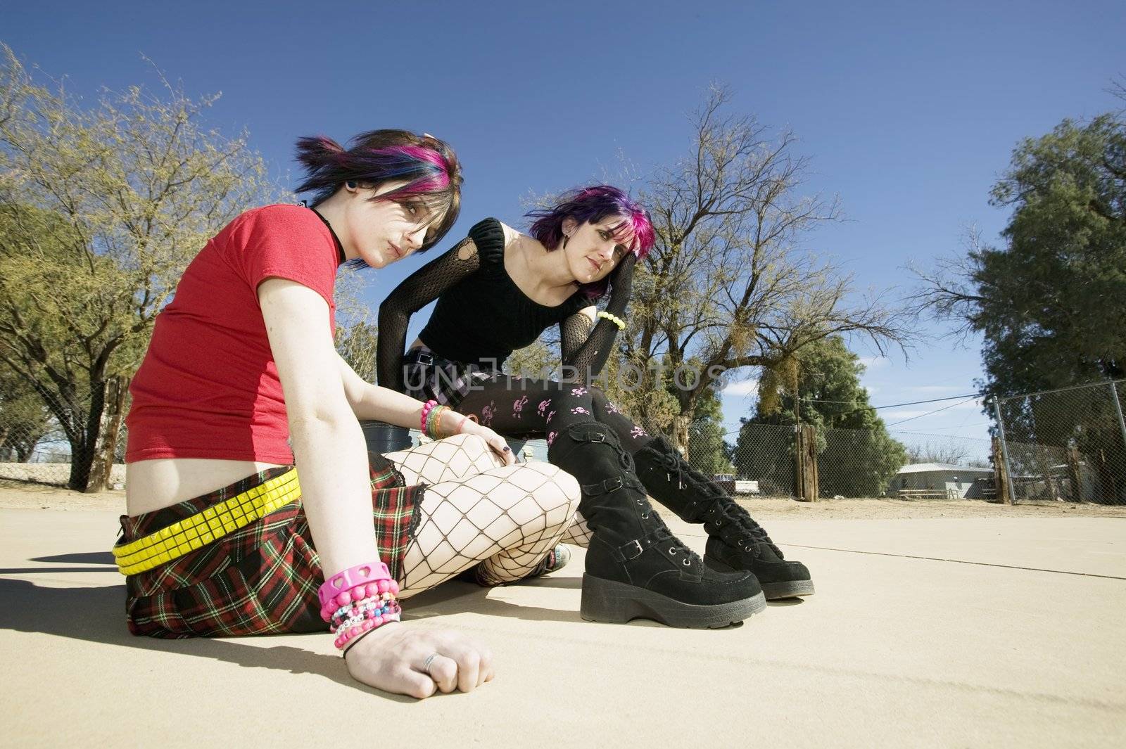 Two Punk Girls Sitting on a cement playground