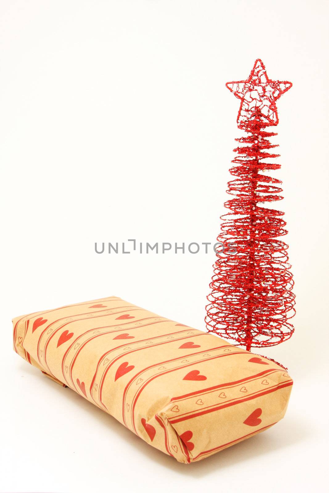 A wrapped present and red ornamental christmas tree shot on white, isolated and background intentionally blown out