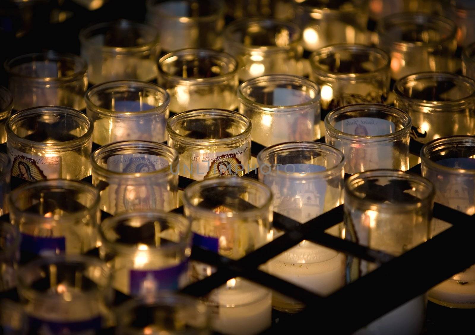 Virgen Mary candle surrounded by many others on a Catholic altar.