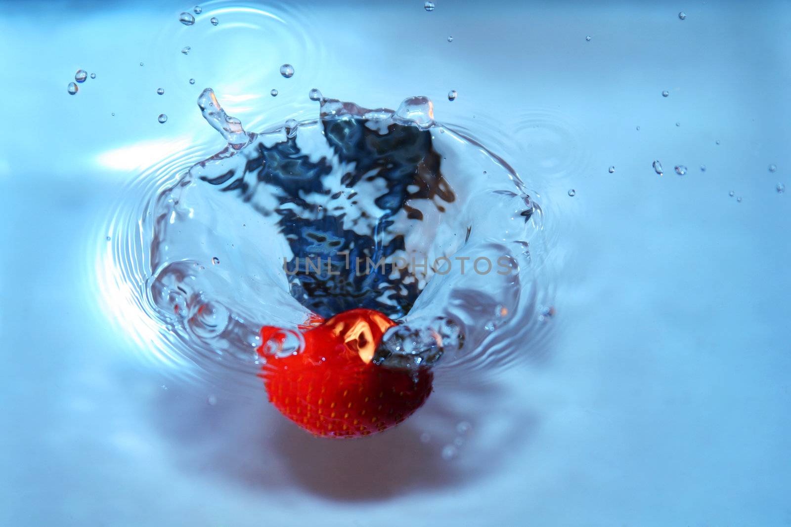 strawberry falling into water, splashing water. freshness and purity implied