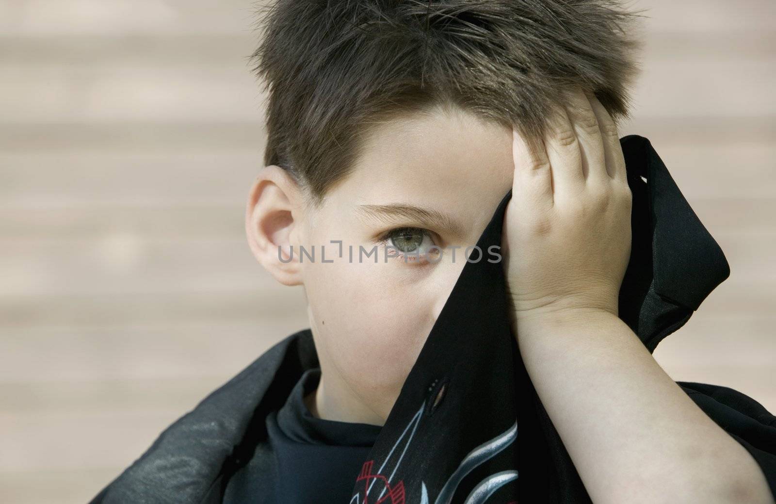 Little boy hides his face behind the tail of his own shirt.